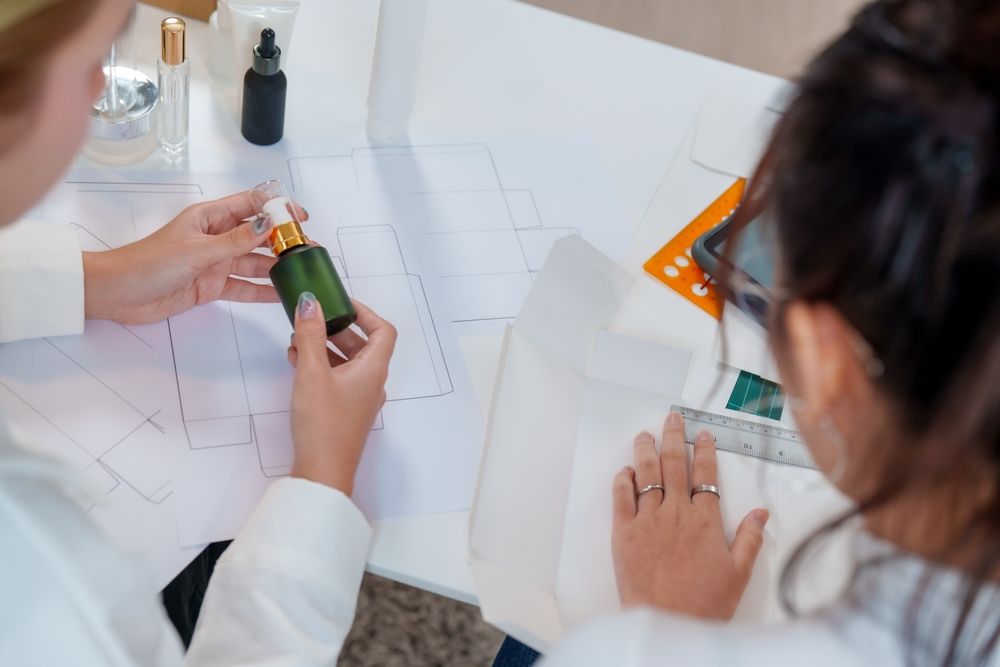 Two women looking at plans while holding a glass cylinder round with a metal-shelled treatment pump