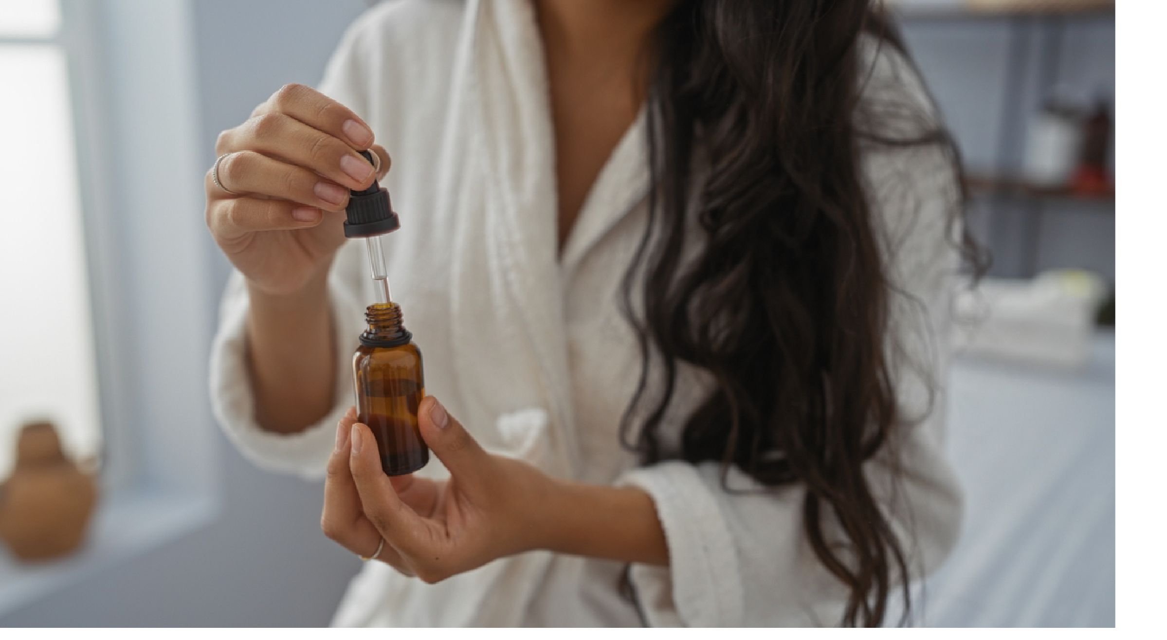 A woman applying serum inside an amber boston round with a dropper
